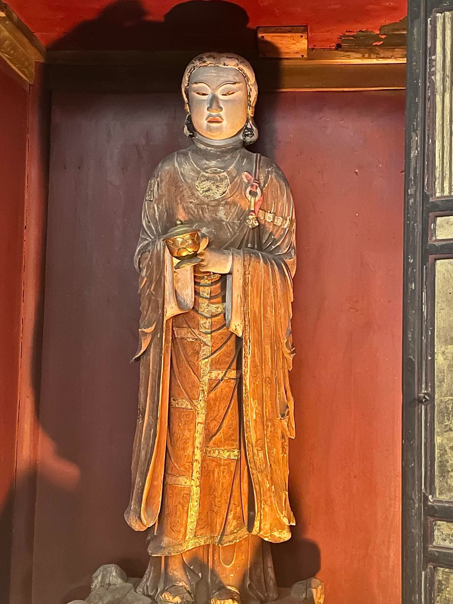 赤い厨子の中に静かに立つ仏像