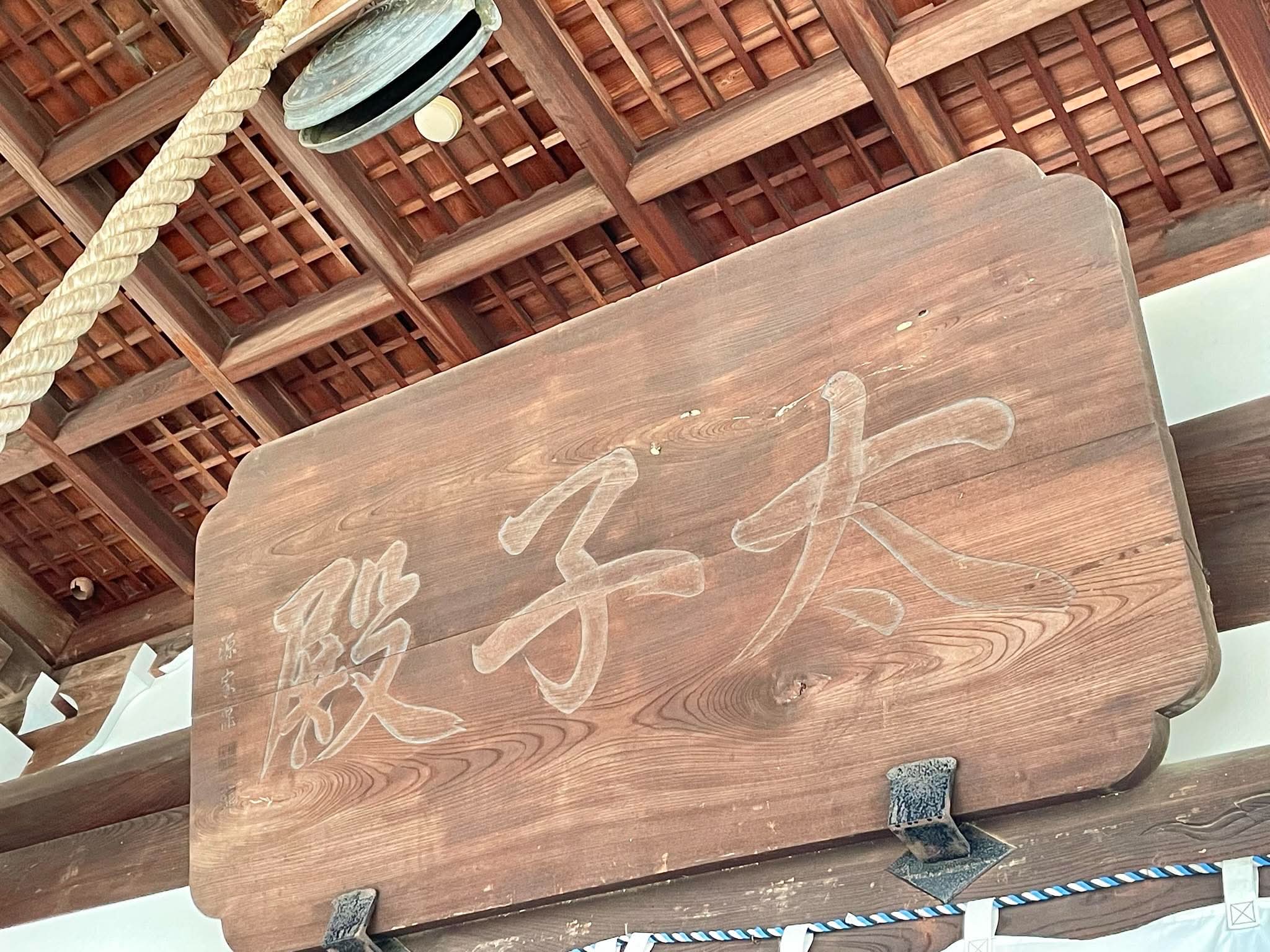 木組みの堂に掲げられた扁額と鐘